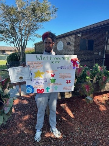 Ishir Williams holding his 2nd place poster while smiling. 
