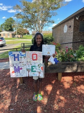 Kayden Fredrick smiles while holding the 1st place poster. 