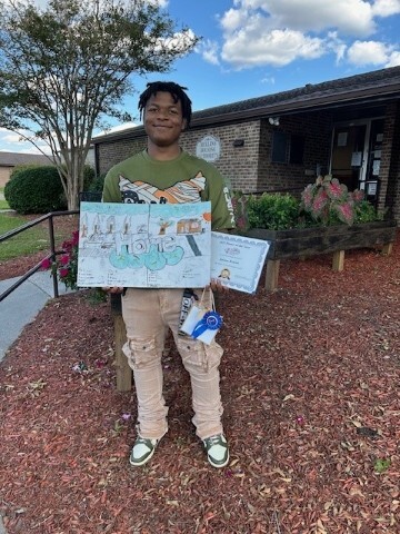 Xavion Reaves holding his 1st place poster.jpg
