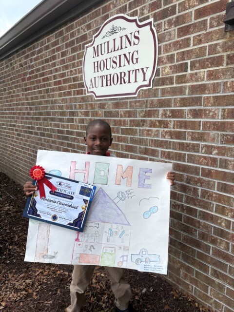 Antonio Carmichael holding up his drawing and winning ribbon. 