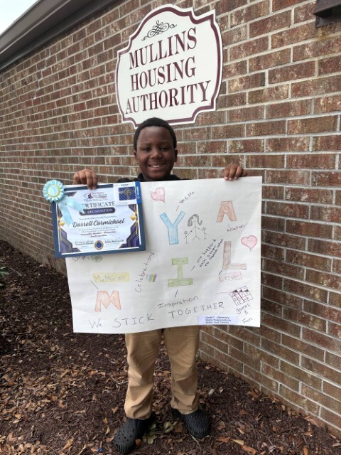 Darrell Carmichael smiles while holding his poster and ribbon. 