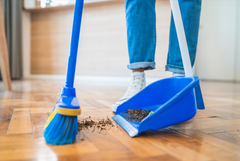 Dustpan and broom with someone cleaning the floor. 
