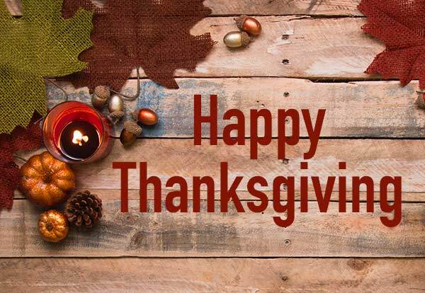 The words "Happy Thanksgiving" on top of a wooden background with fall foliage.